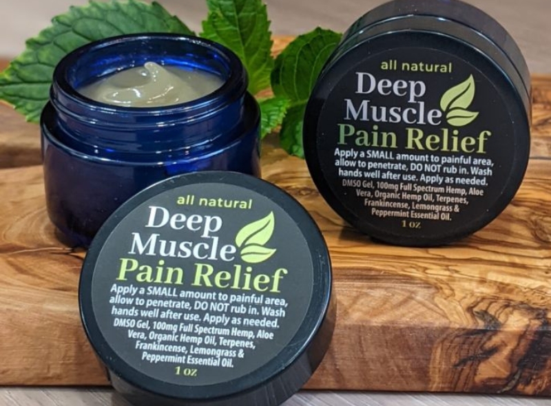 Deep Muscle DMSO pain Gel in blue jar with lid off on wooden base